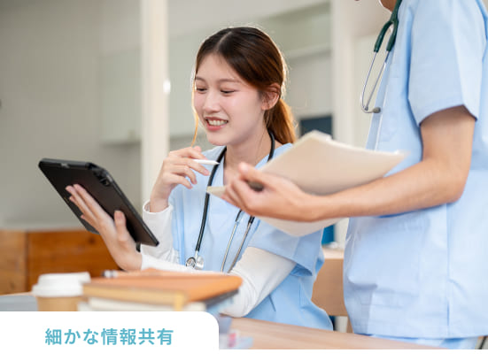 タブレットを見て情報交換している看護師