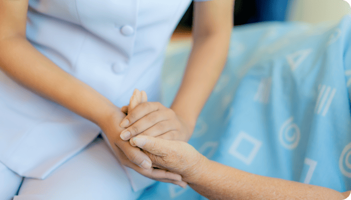 ベッドサイドで入居者に寄り添い手を握る看護師